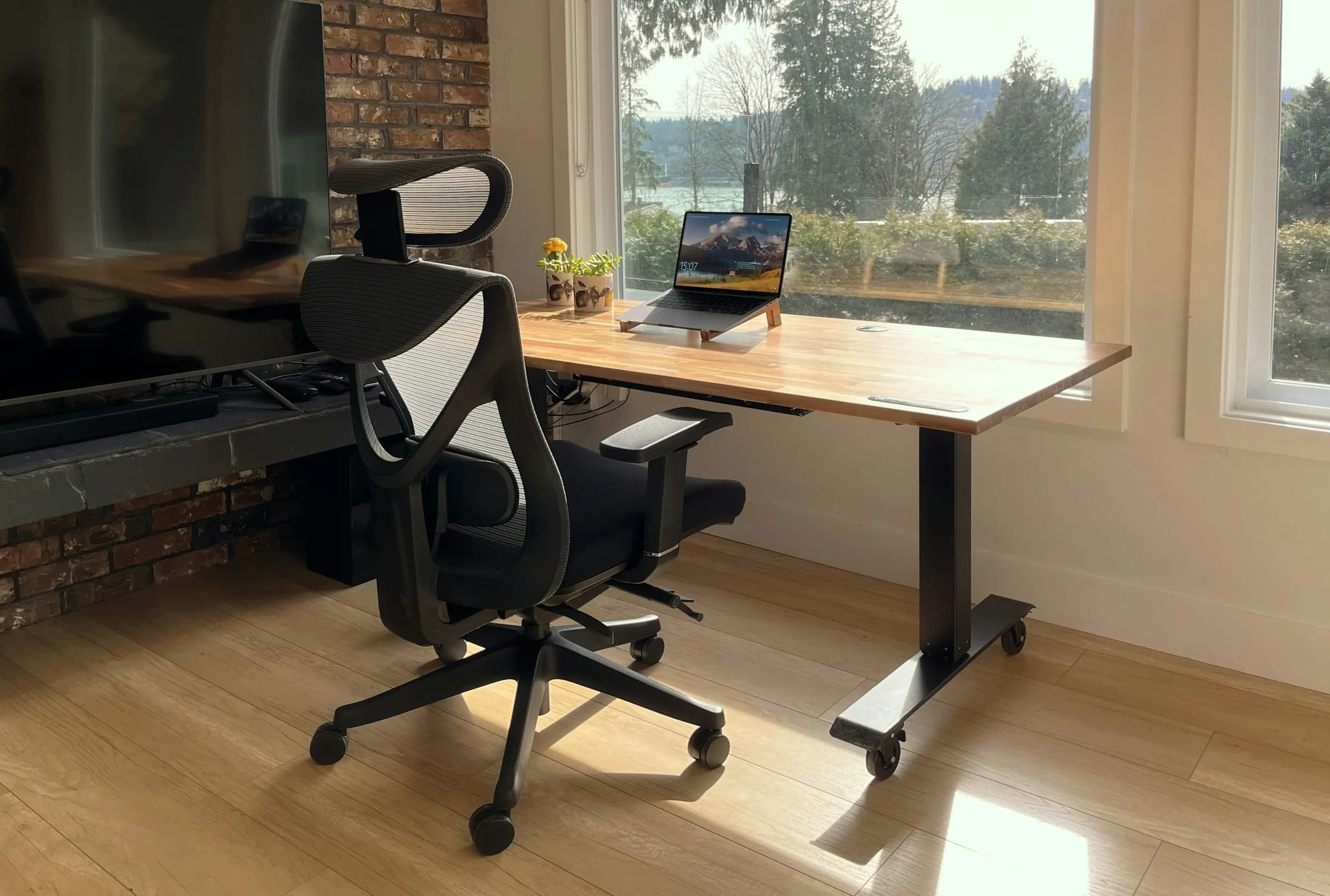 Bright office desk with a laptop beside a large window