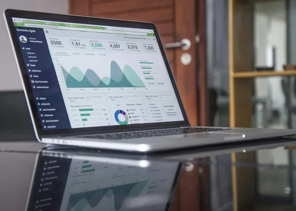 Laptop showing marketing charts on a glass desk