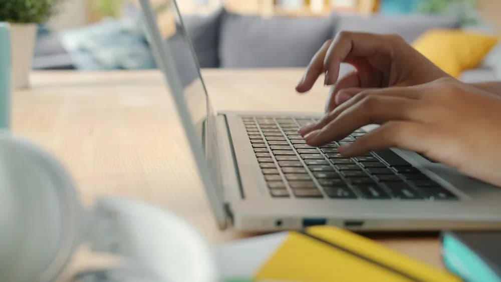 Hands typing on a laptop at a bright desk